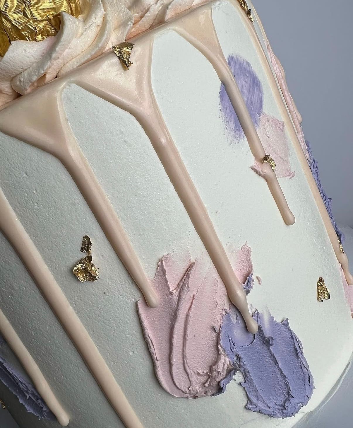 Pastel drip cake with pink and lavender buttercream swatches and gold leaf